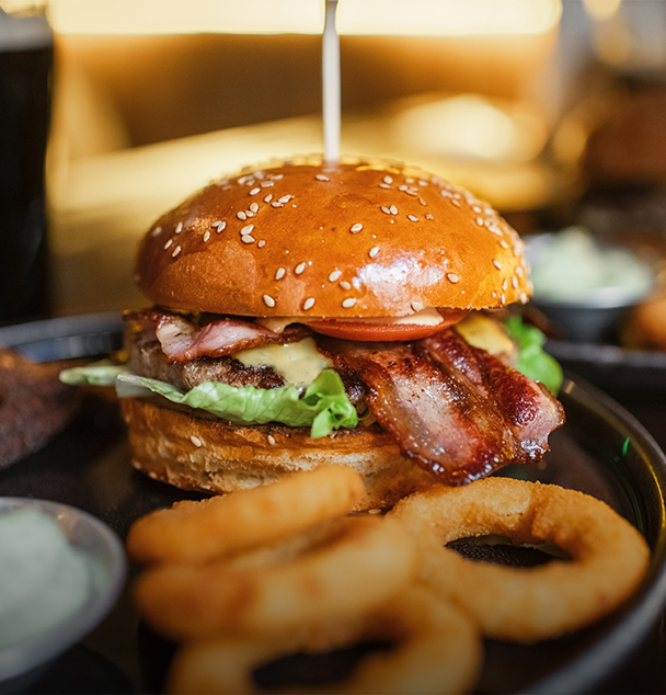 a burger with bacon and onion rings on a plate