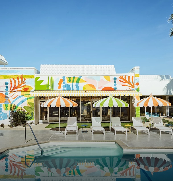 a pool with umbrellas and chairs in front of a building