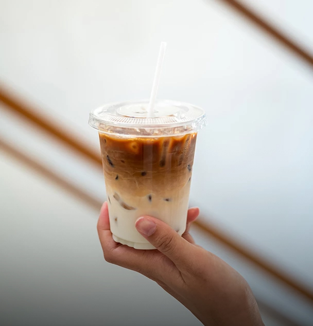 a hand holding a plastic cup of iced coffee