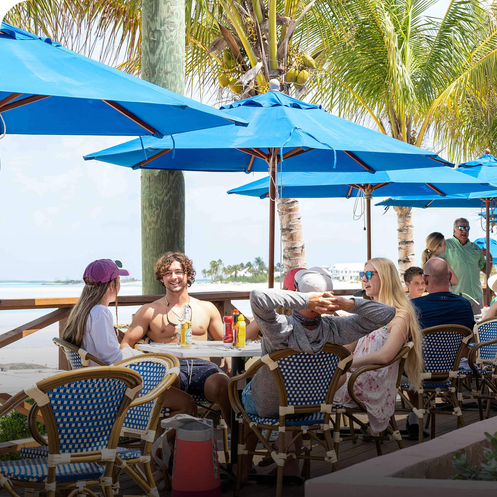 a group of people sitting at a table under umbrellas