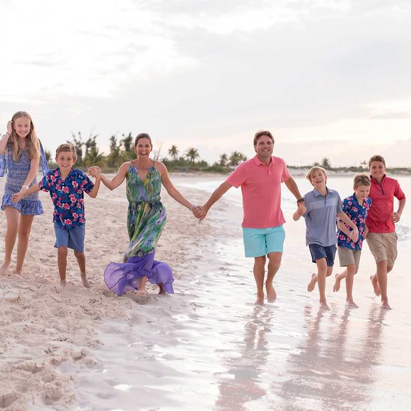 a group of people holding hands and running on a beach