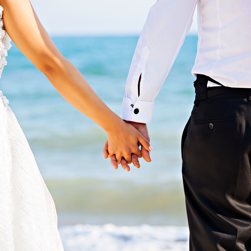 a man and woman holding hands on a beach