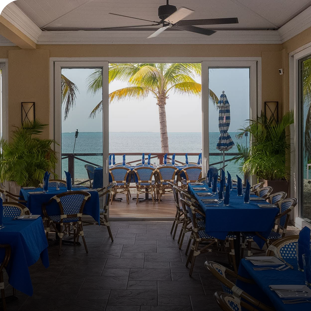 a room with tables and chairs and a view of the ocean