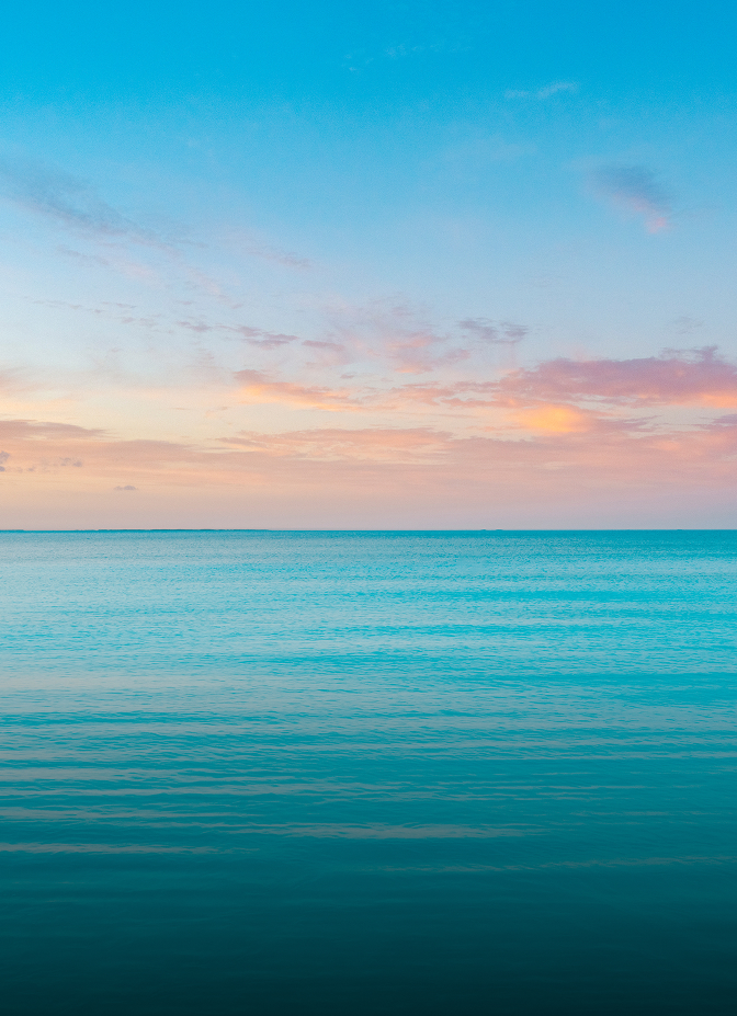 a blue ocean with pink and yellow clouds
