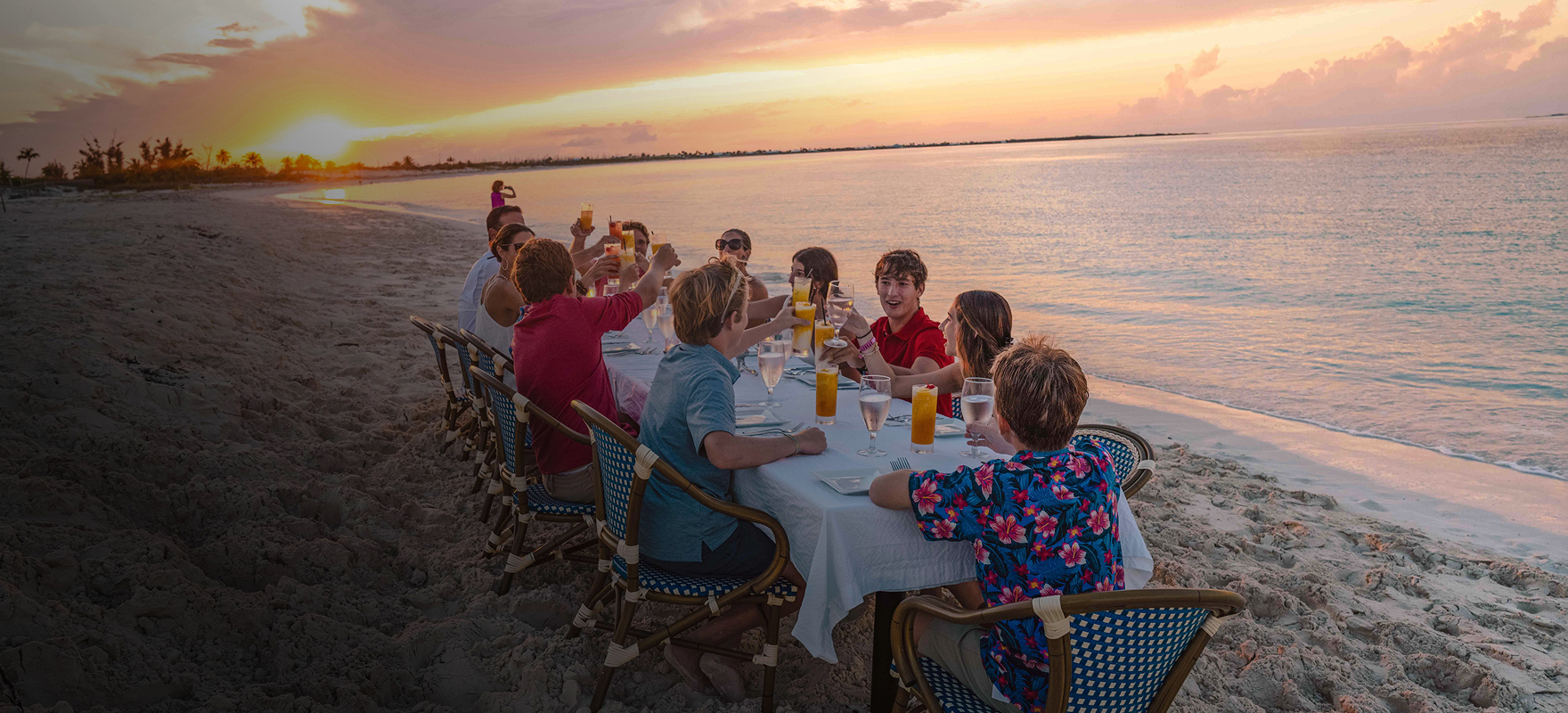 a group of people sitting at a table on a beach