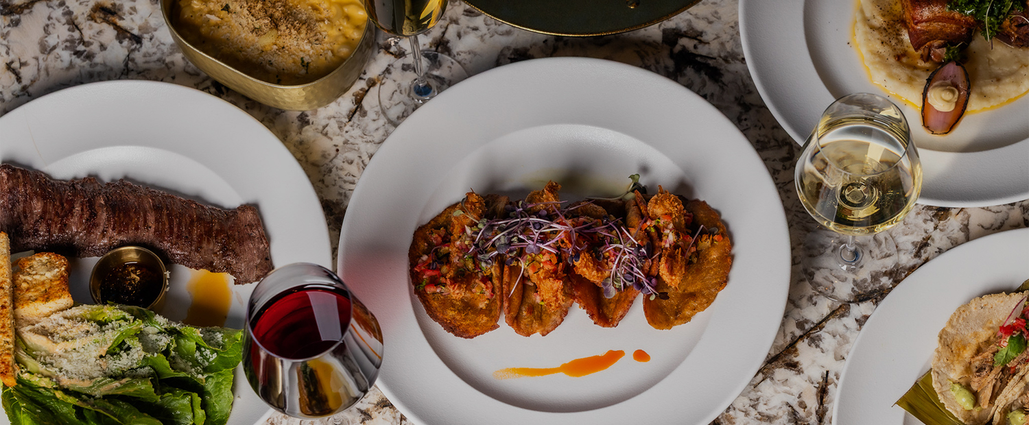 food on a plate next to a glass of wine