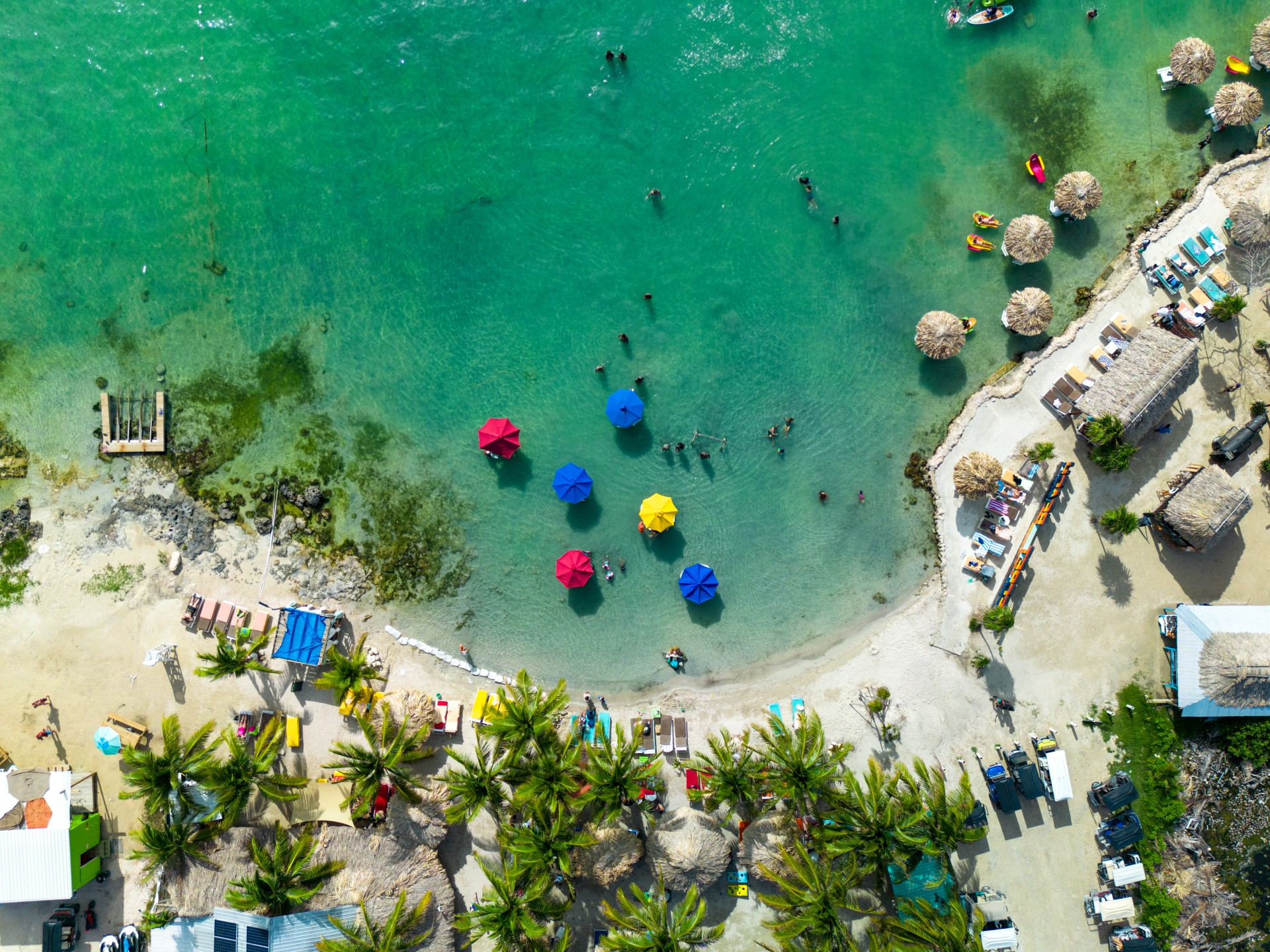 aerial view of a beach with umbrellas and people in the water