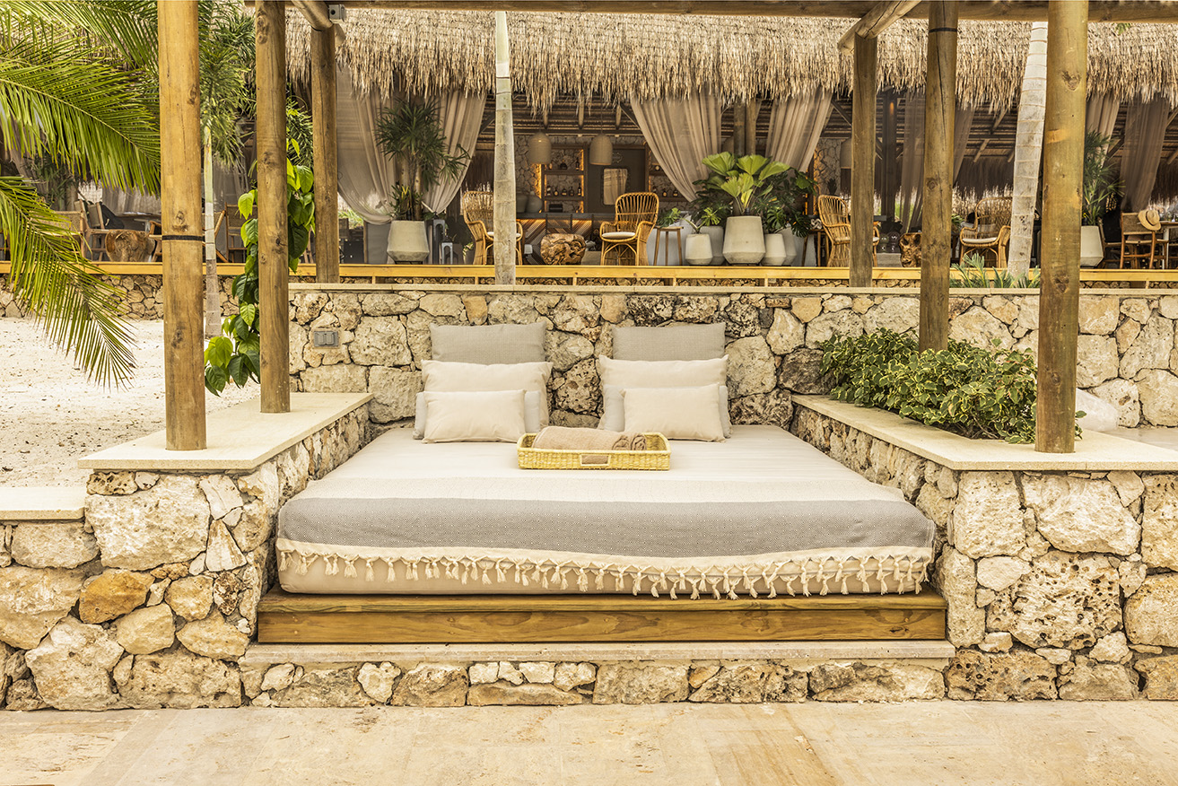 a bed with pillows on a stone wall