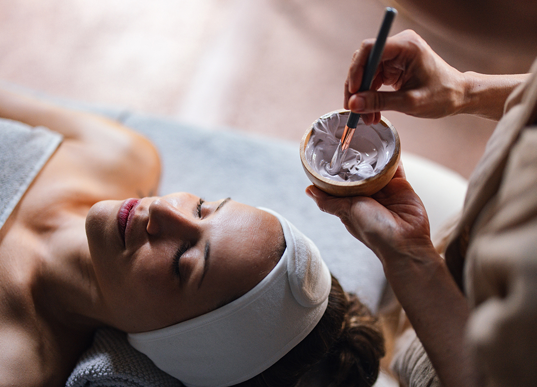 a woman lying down with a bowl of white cream