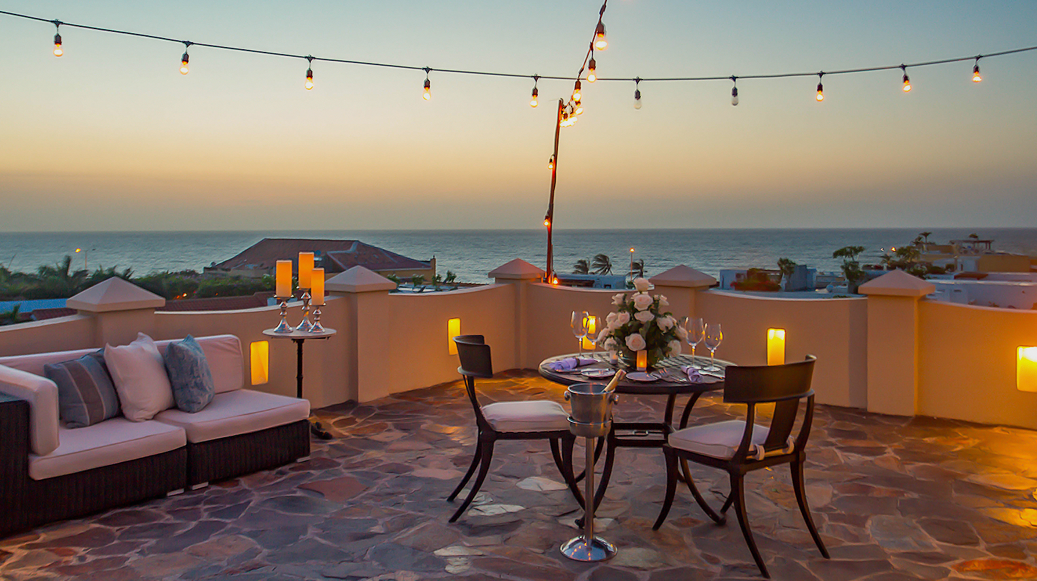 a table and chairs on a patio with a view of the ocean