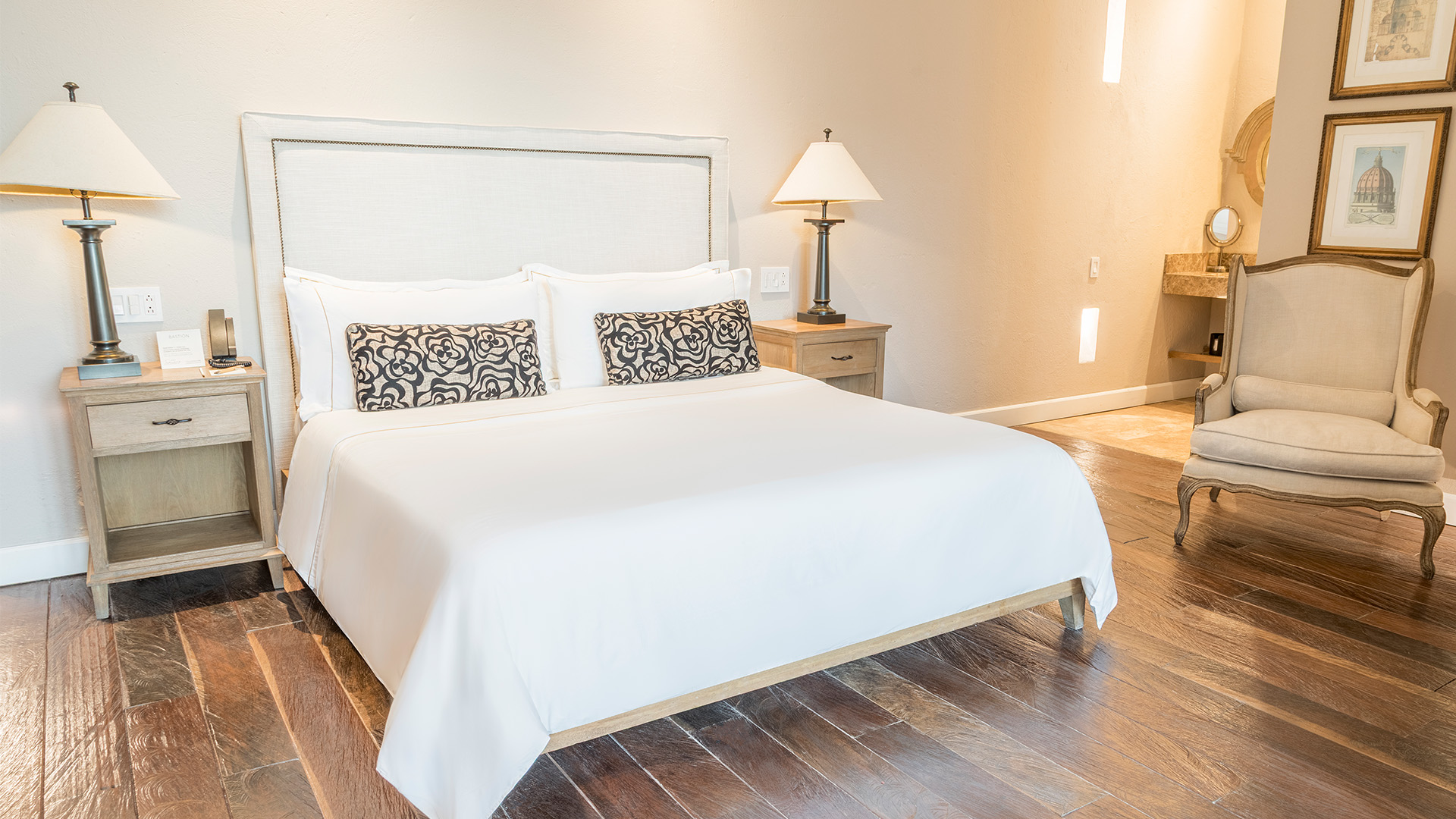 a bed with a white bedding and a lamp on a wooden floor