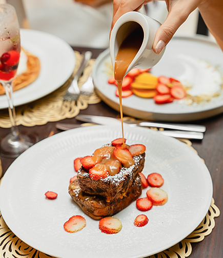 a person pouring a brown sauce on a piece of food