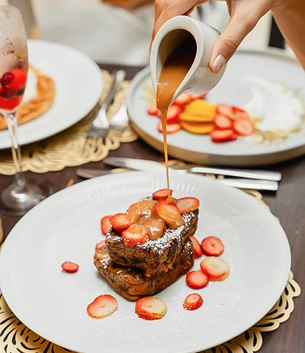 a person pouring a brown sauce on a piece of food