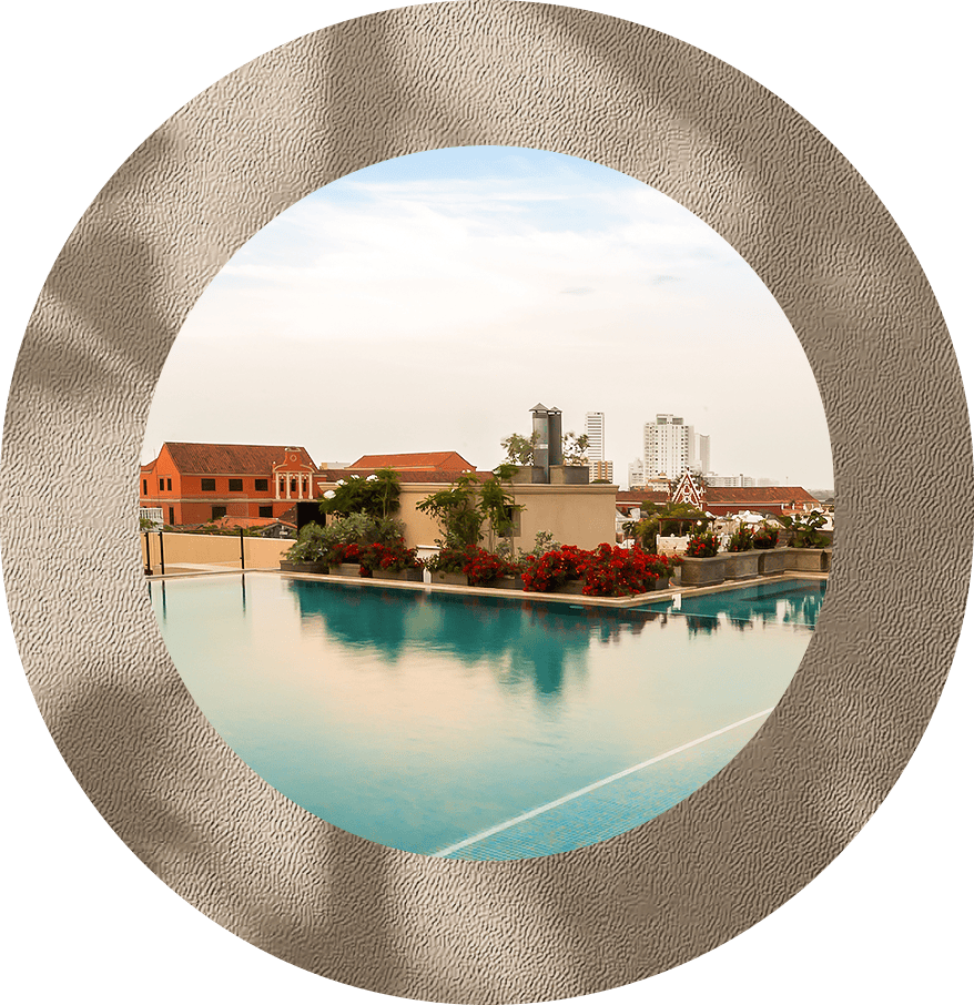 a pool with flowers and buildings in the background