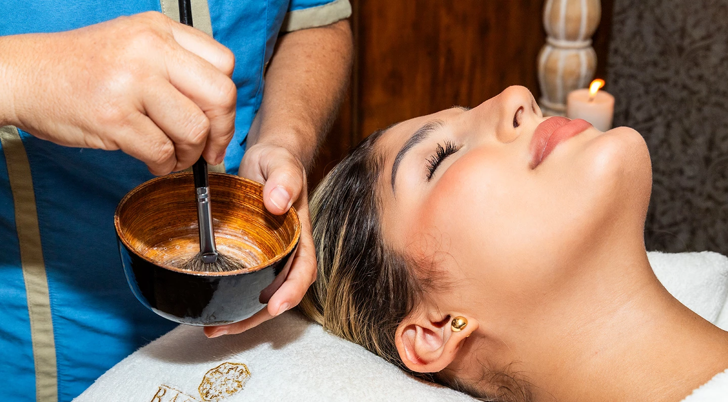 a woman lying down with her eyes closed and a bowl of water