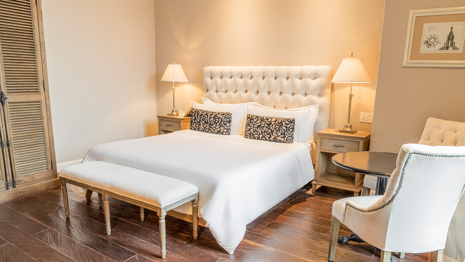 a bed with a white headboard and a table with lamps