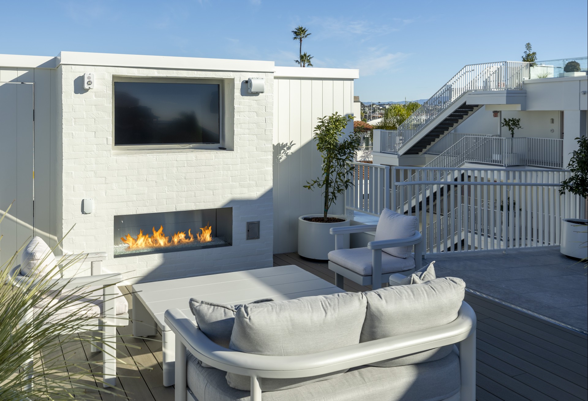 a patio with a fire pit and a white wall