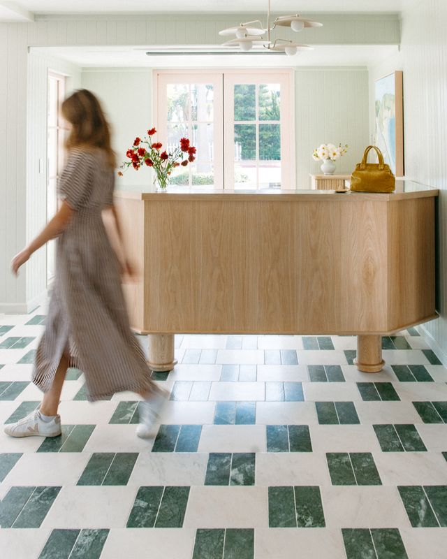 a woman walking in a room with a checkered floor and a counter