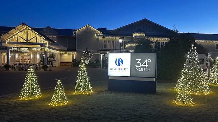 a sign in front of a building with christmas lights