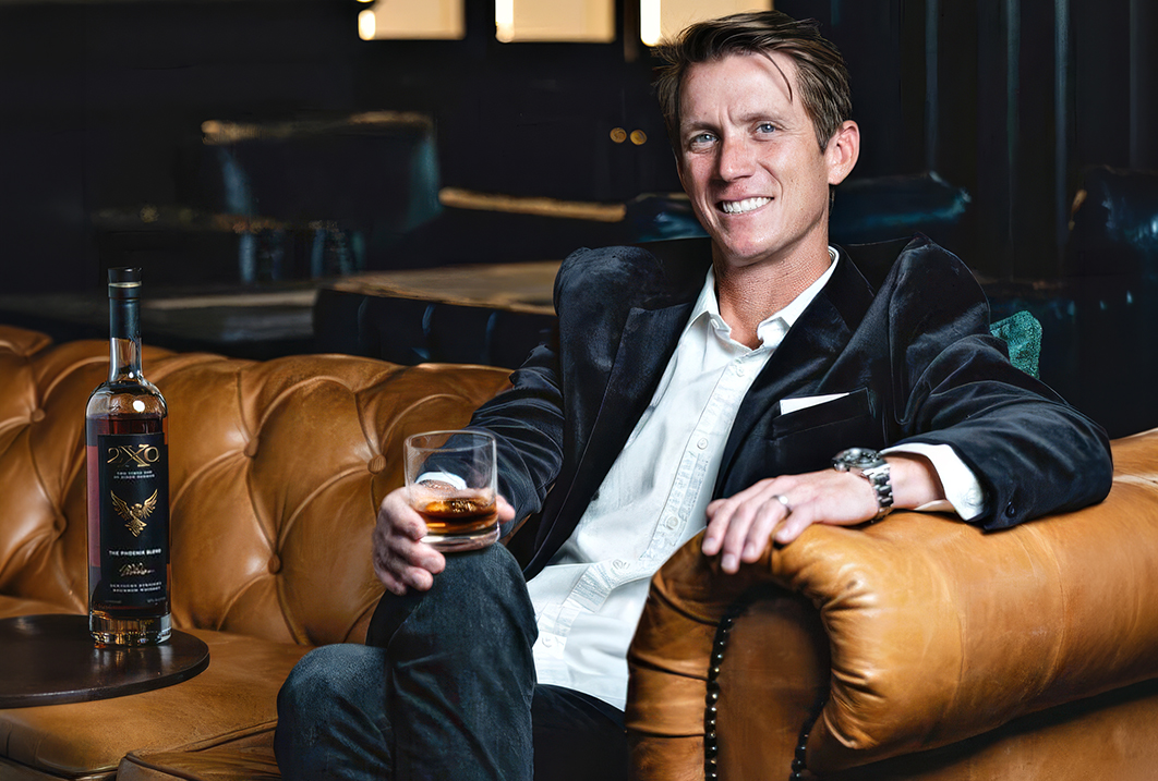 a man sitting on a couch holding a glass of alcohol