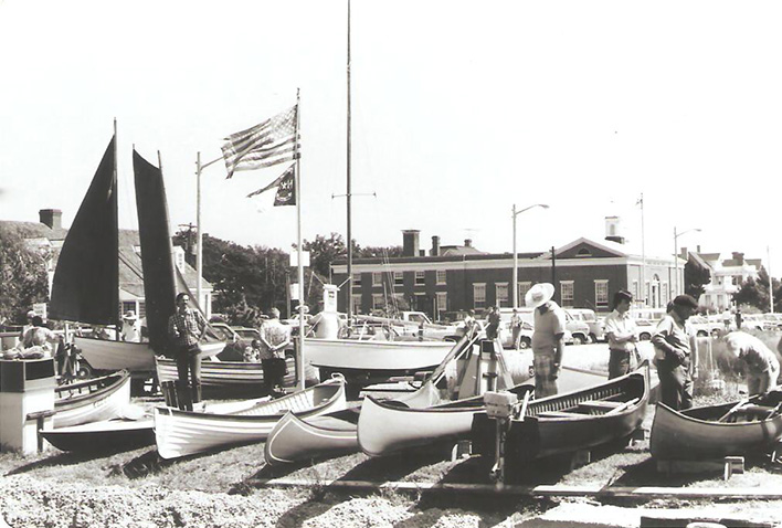 several people standing next to boats