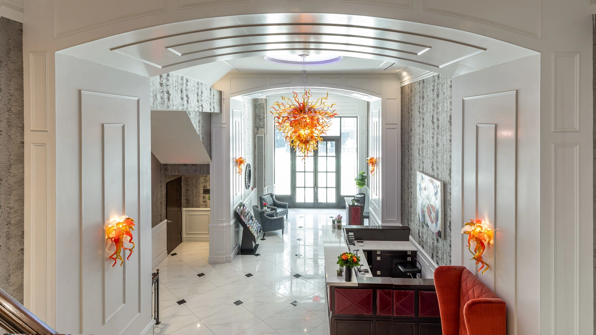 A bright and spacious lobby with a high ceiling, a large chandelier, and a reception desk.