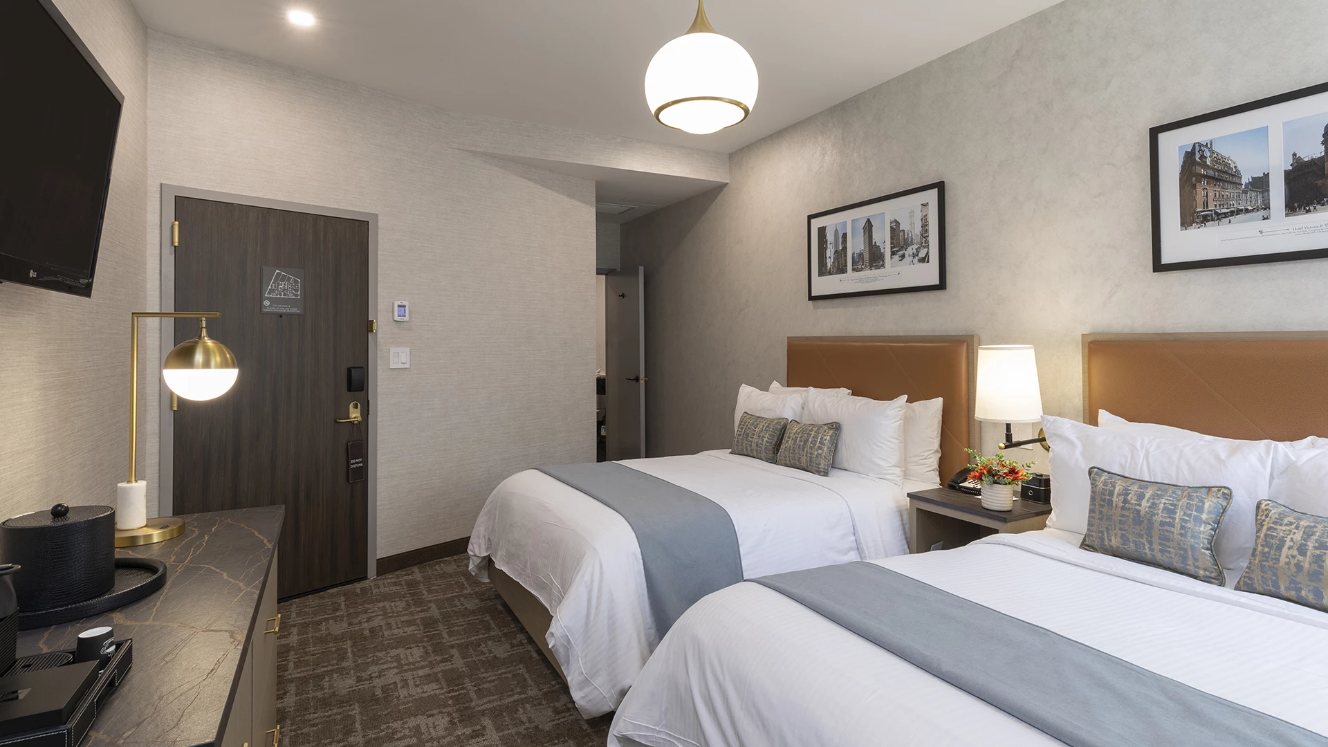 A hotel room with two twin beds, a desk, TV, and lamp.