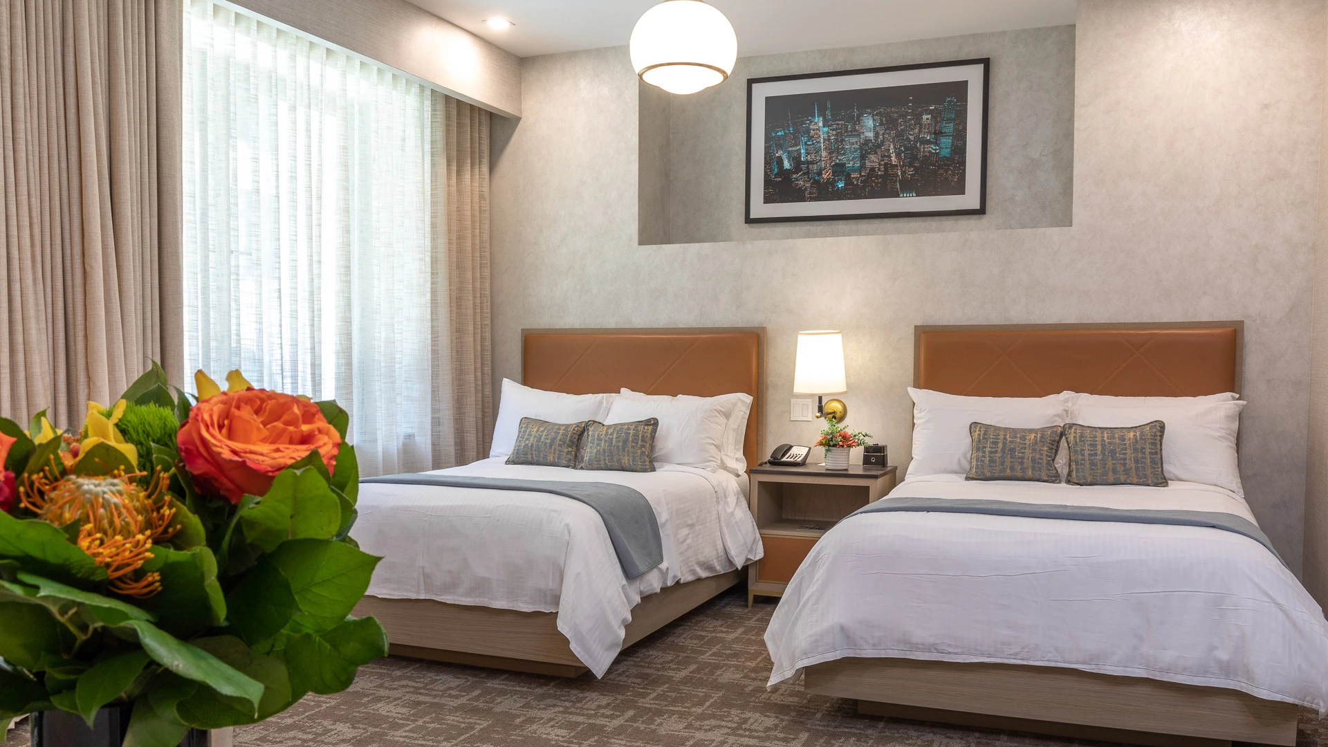 A hotel room with two twin beds, a nightstand, and a window with curtains.