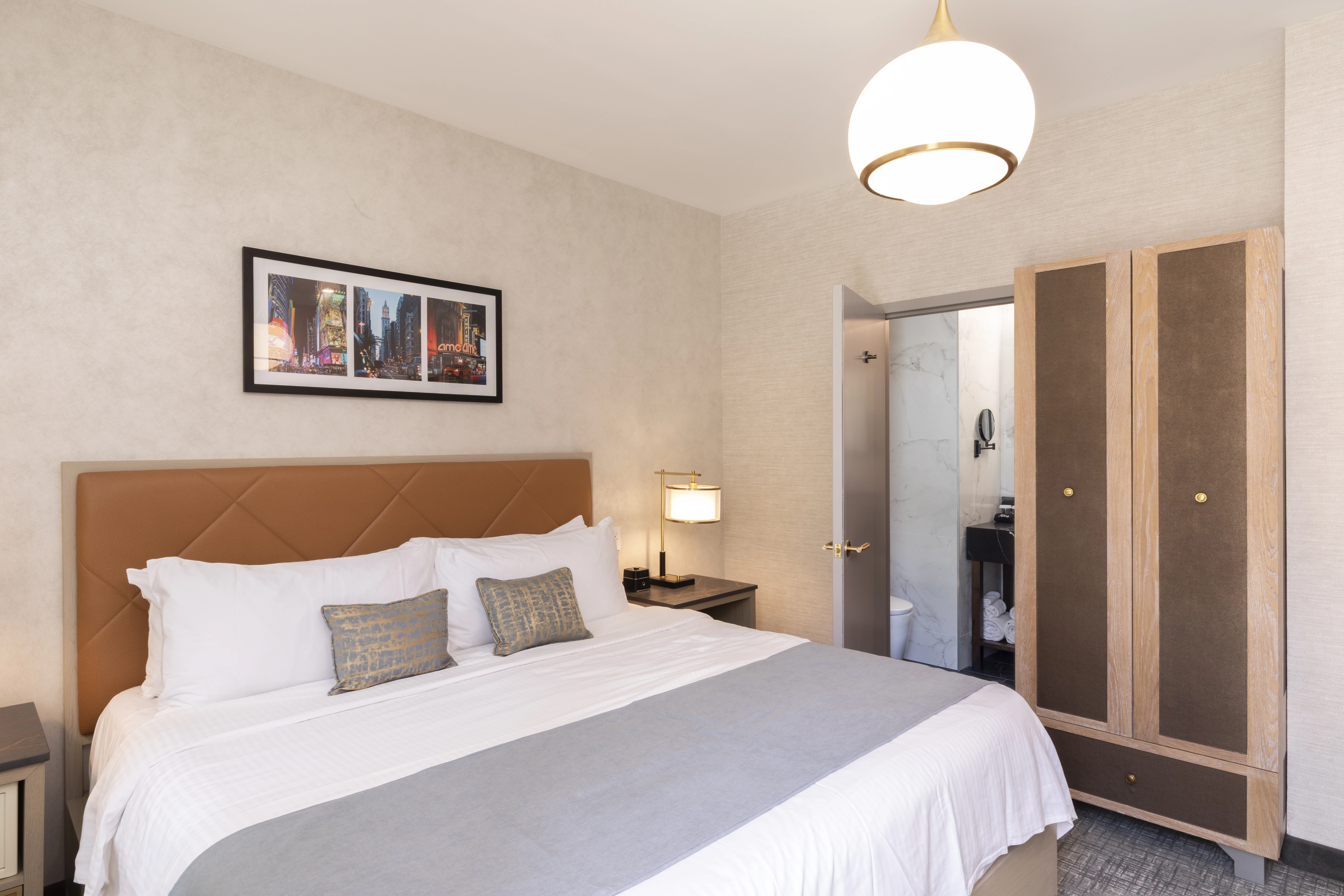 A hotel room with a bed, wardrobe, nightstand, and lamp.