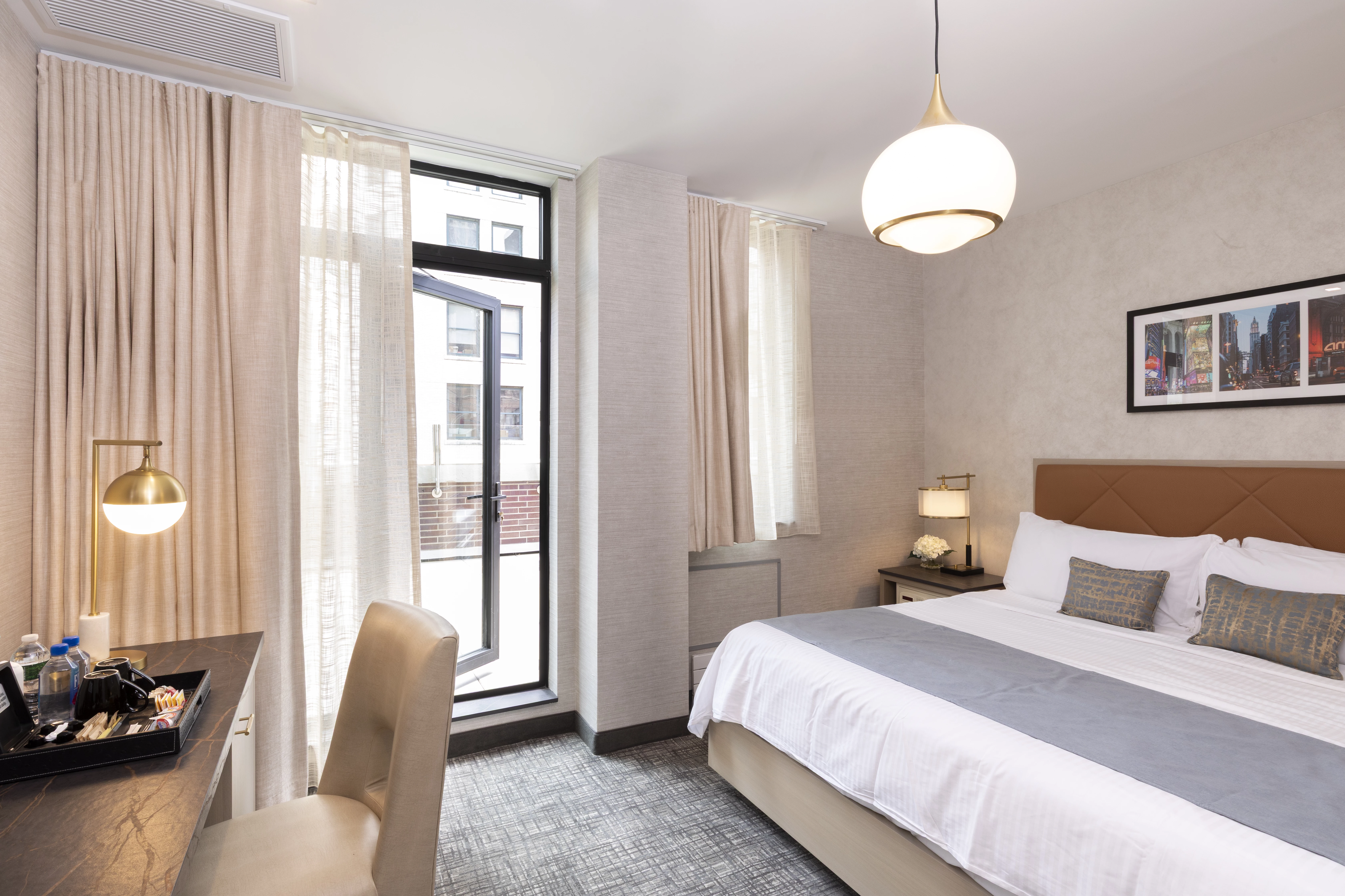 A hotel room with a bed, desk, chair, and window