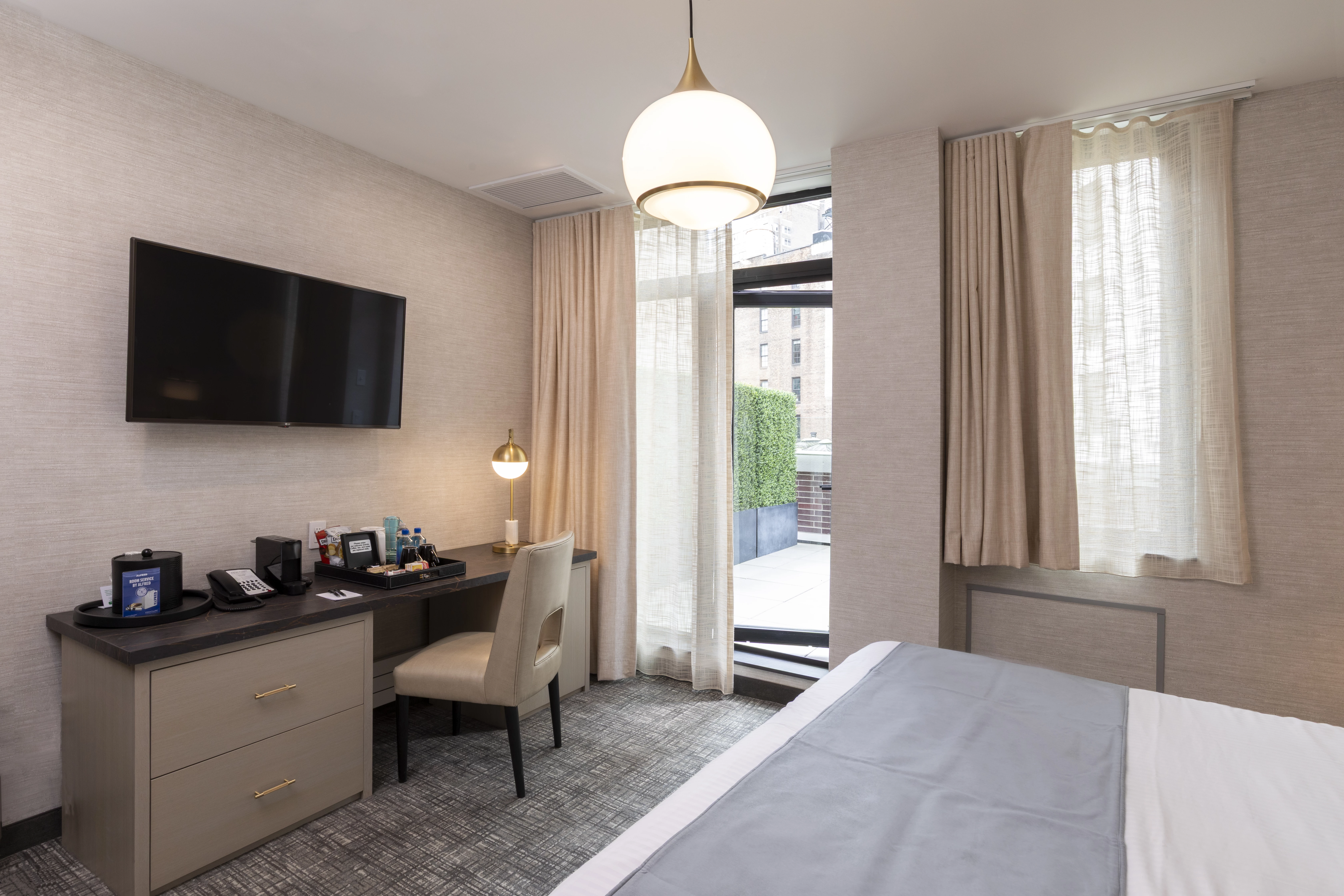 A hotel room with a bed, desk, chair, TV, and window