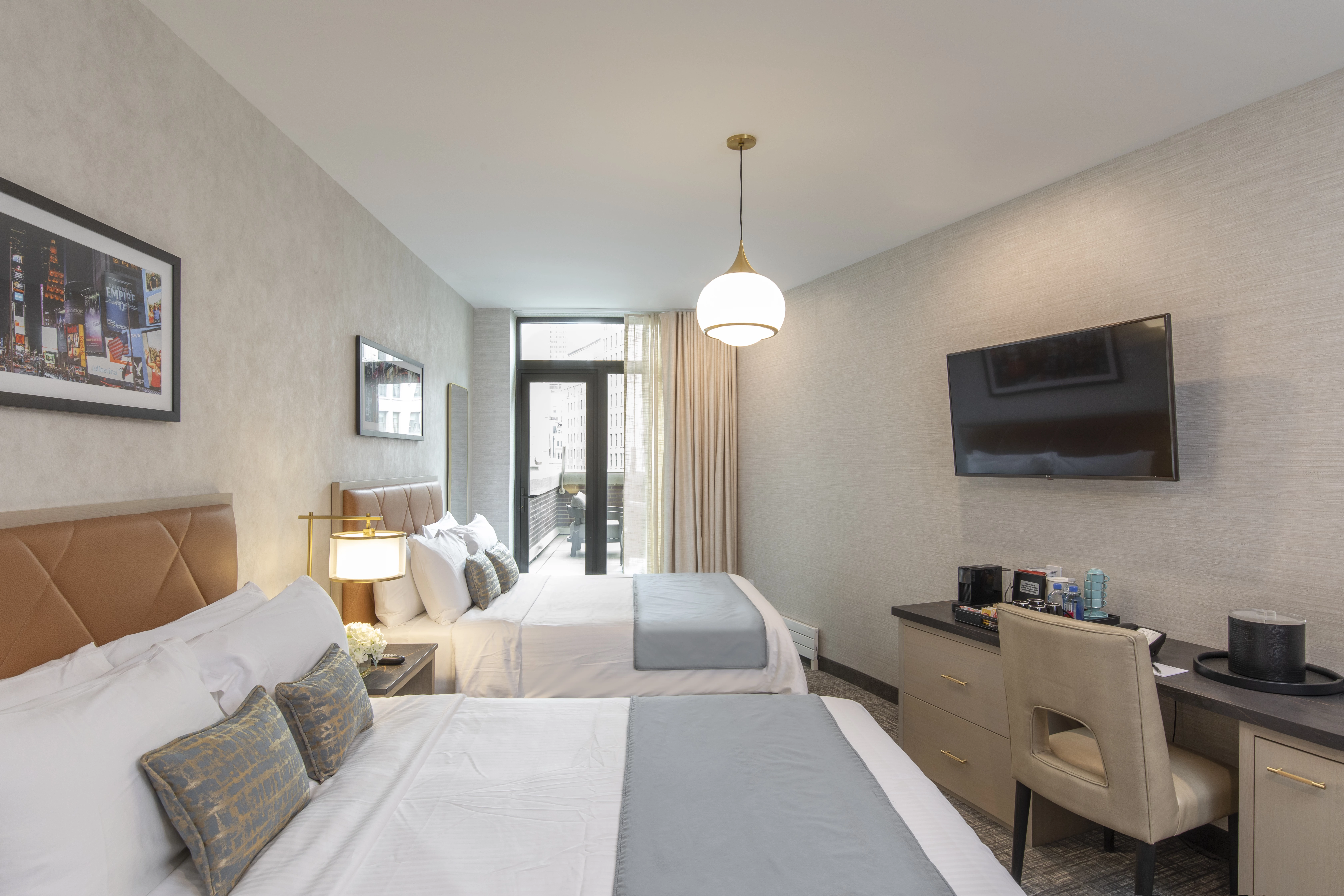 A hotel room with two beds, a desk, and a TV on the wall.