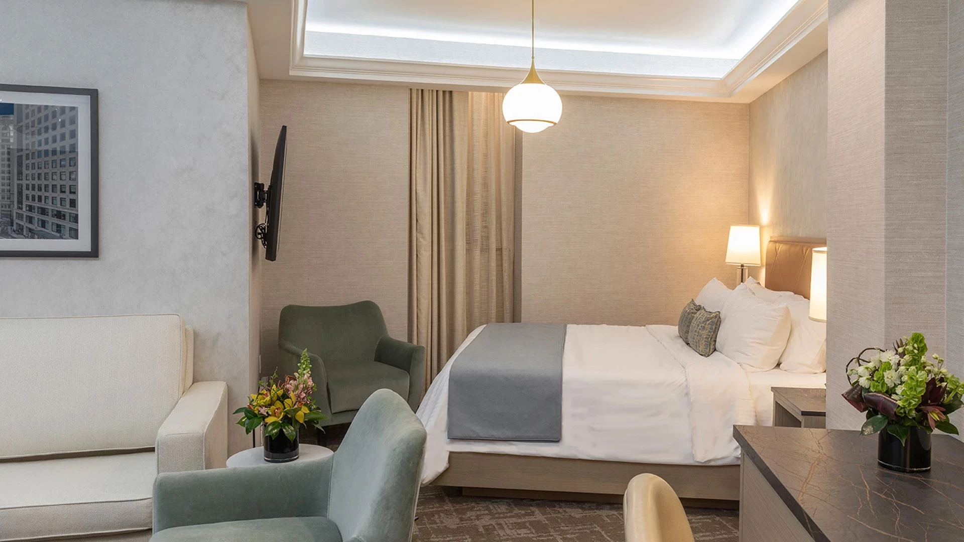 A wide view of a hotel room with a bed, sofa, desk, and chair.