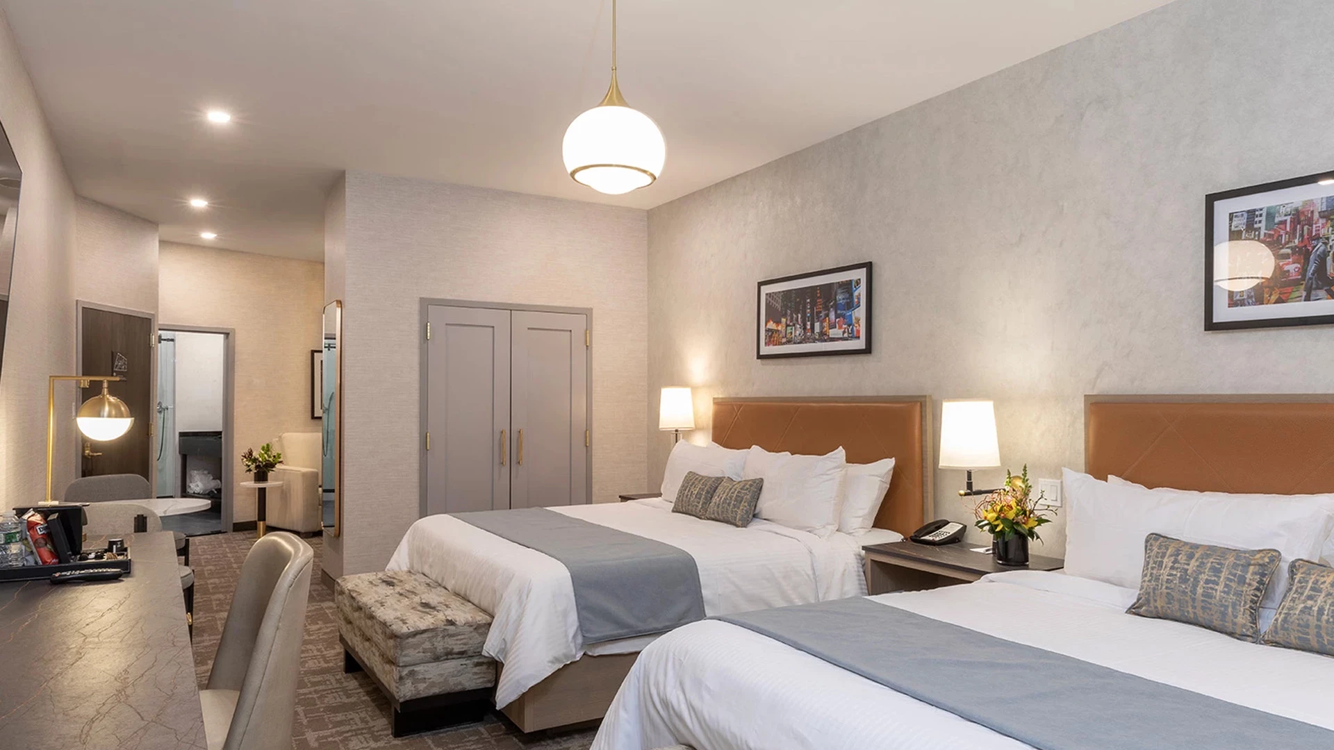A hotel room with two beds, a desk, and a sitting area.