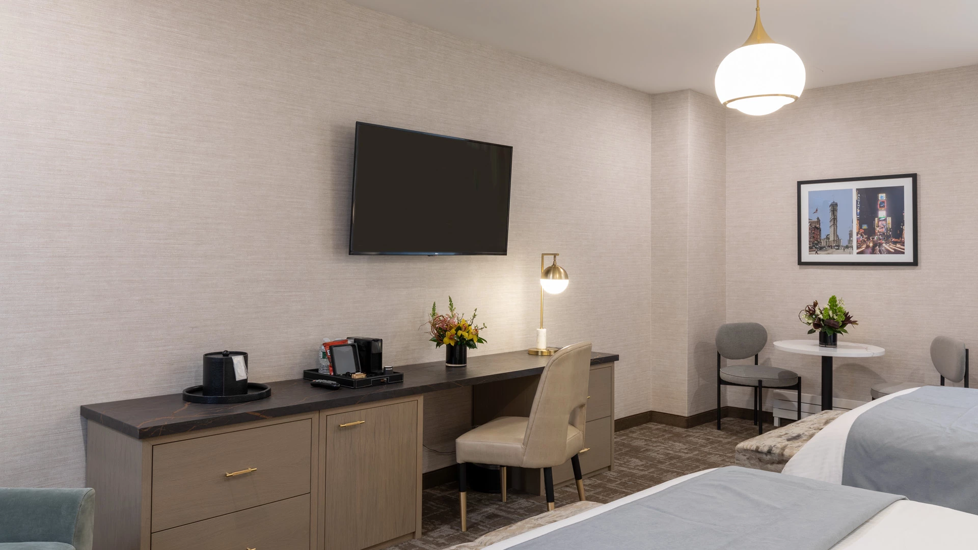 A hotel room with a desk, TV, bed, and chair