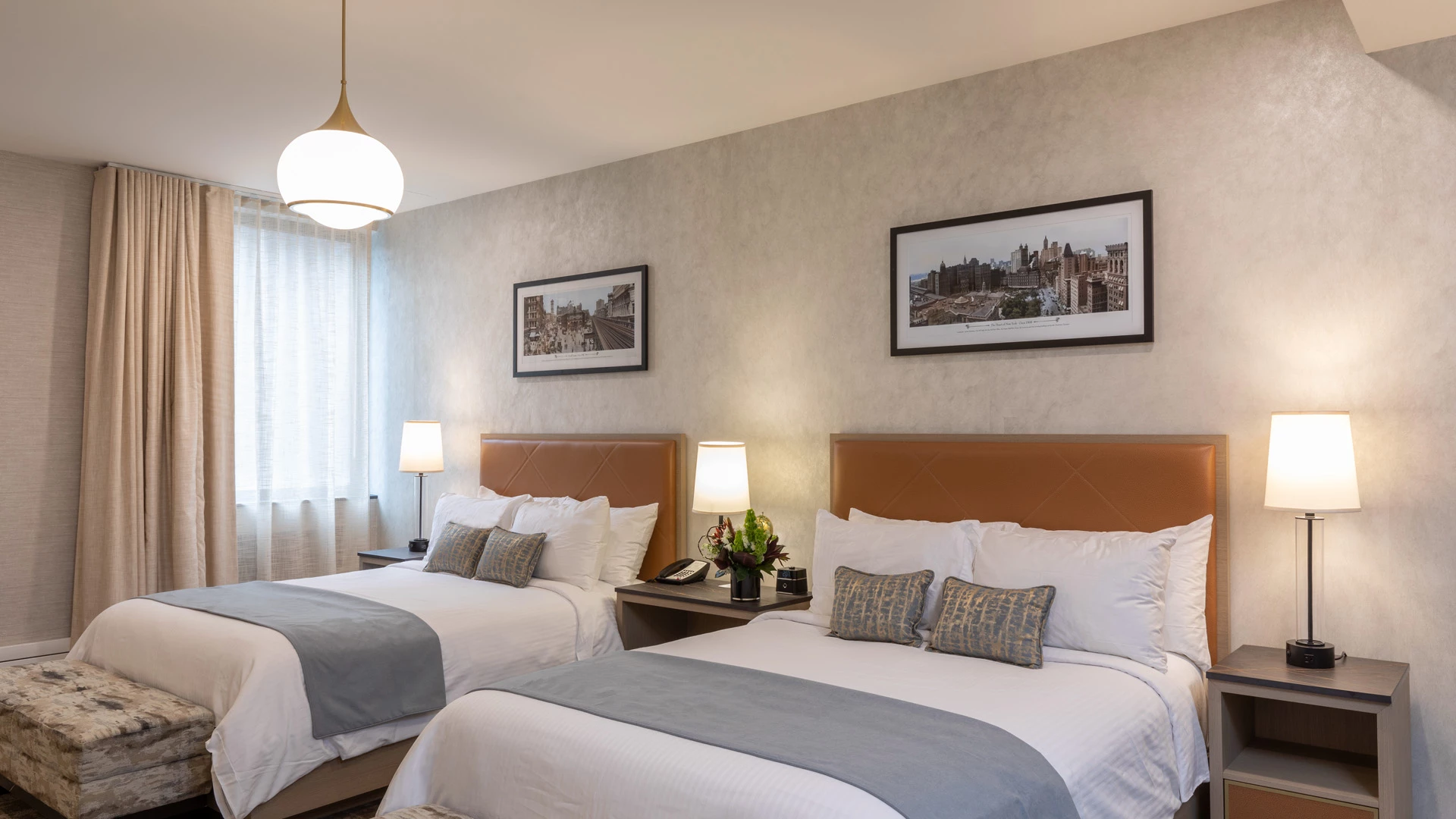 A hotel room with two beds, nightstands, lamps, and framed pictures on the wall.