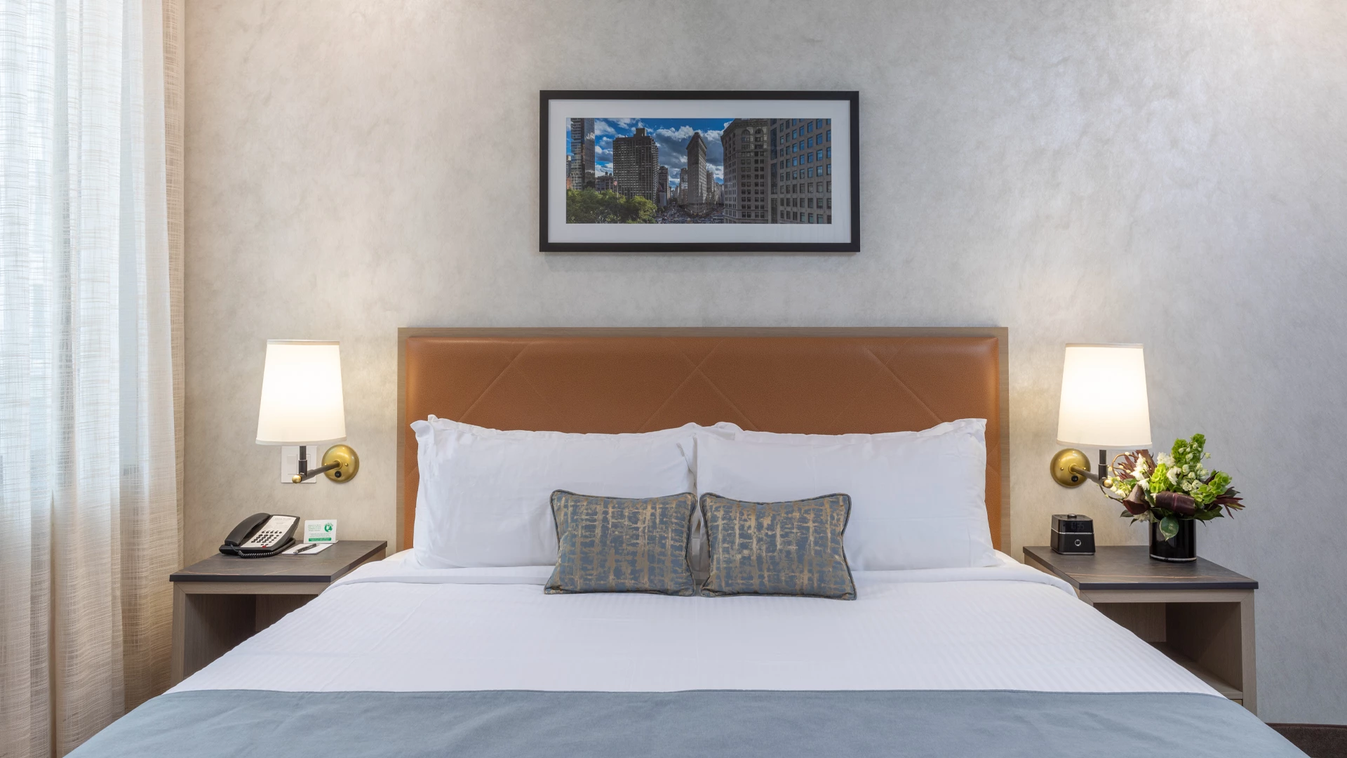A hotel room with a large bed, two nightstands, and a framed picture on the wall