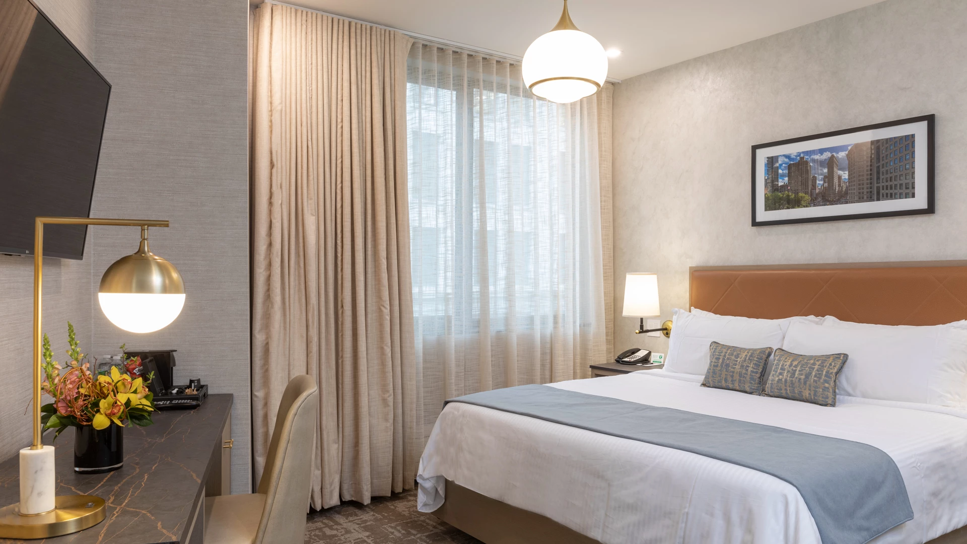 A hotel room with a bed, desk, TV, and window