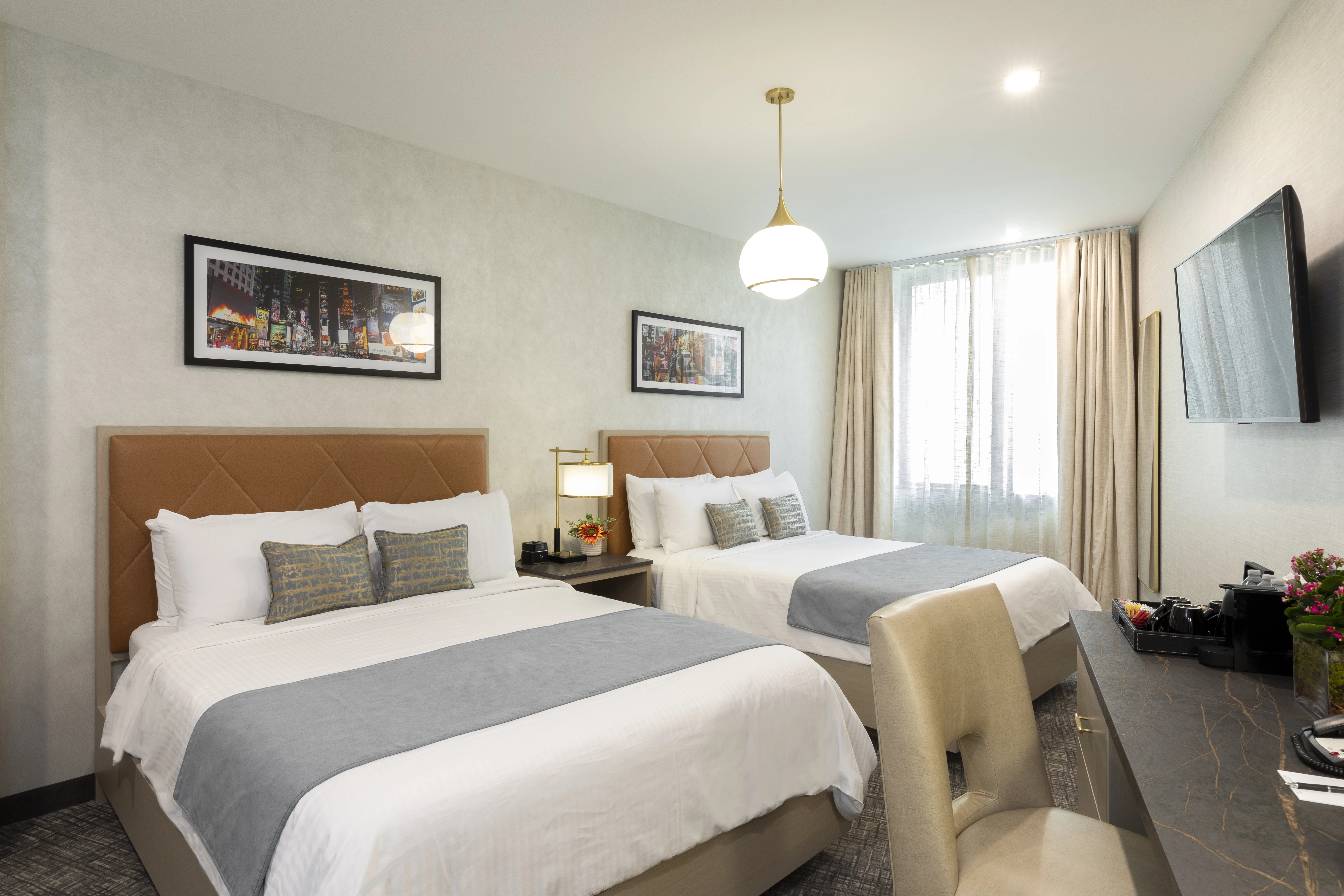 A hotel room with two beds, a desk, and a window.