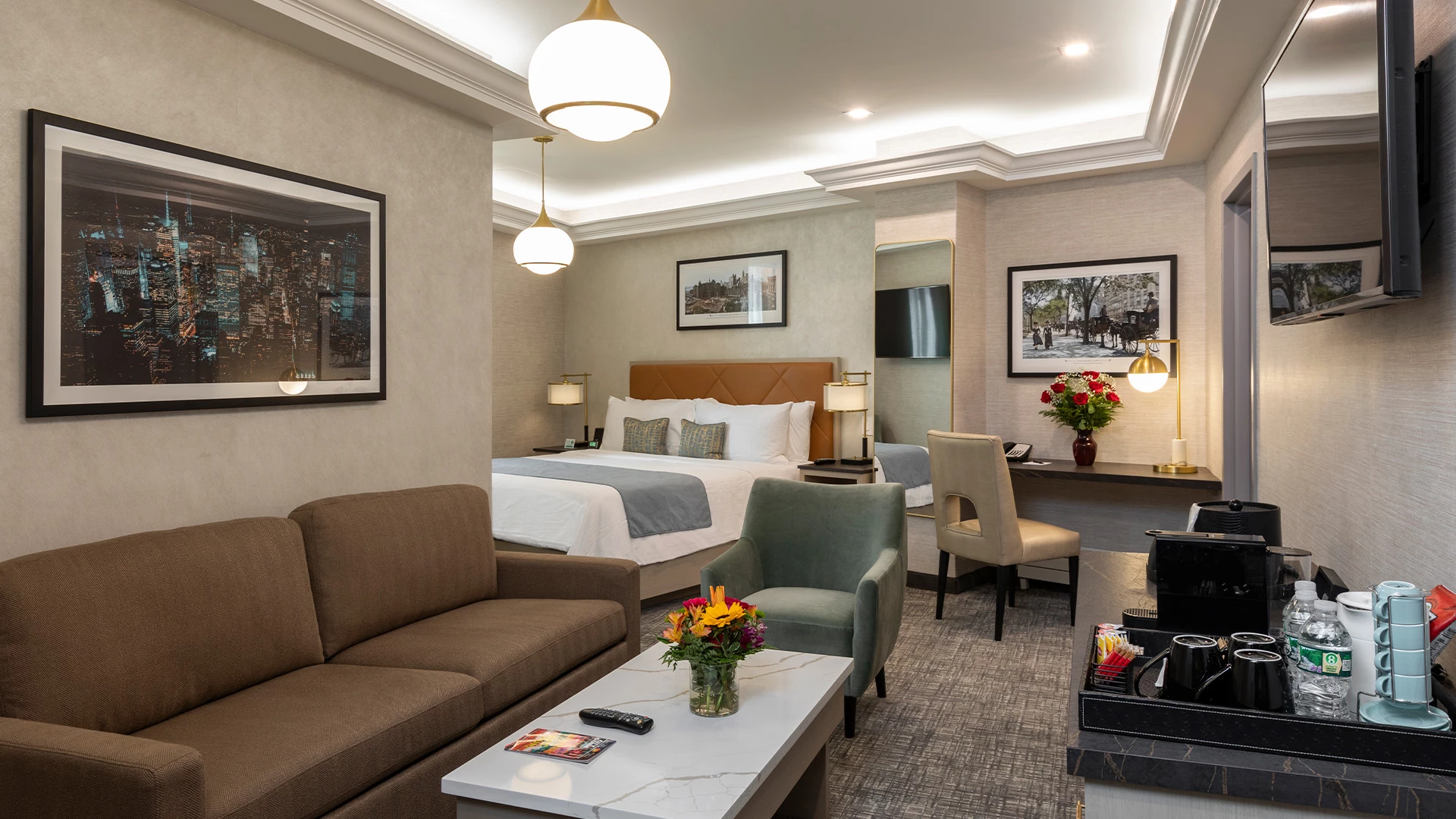 A hotel room with a sofa, coffee table, armchair, bed, and desk.