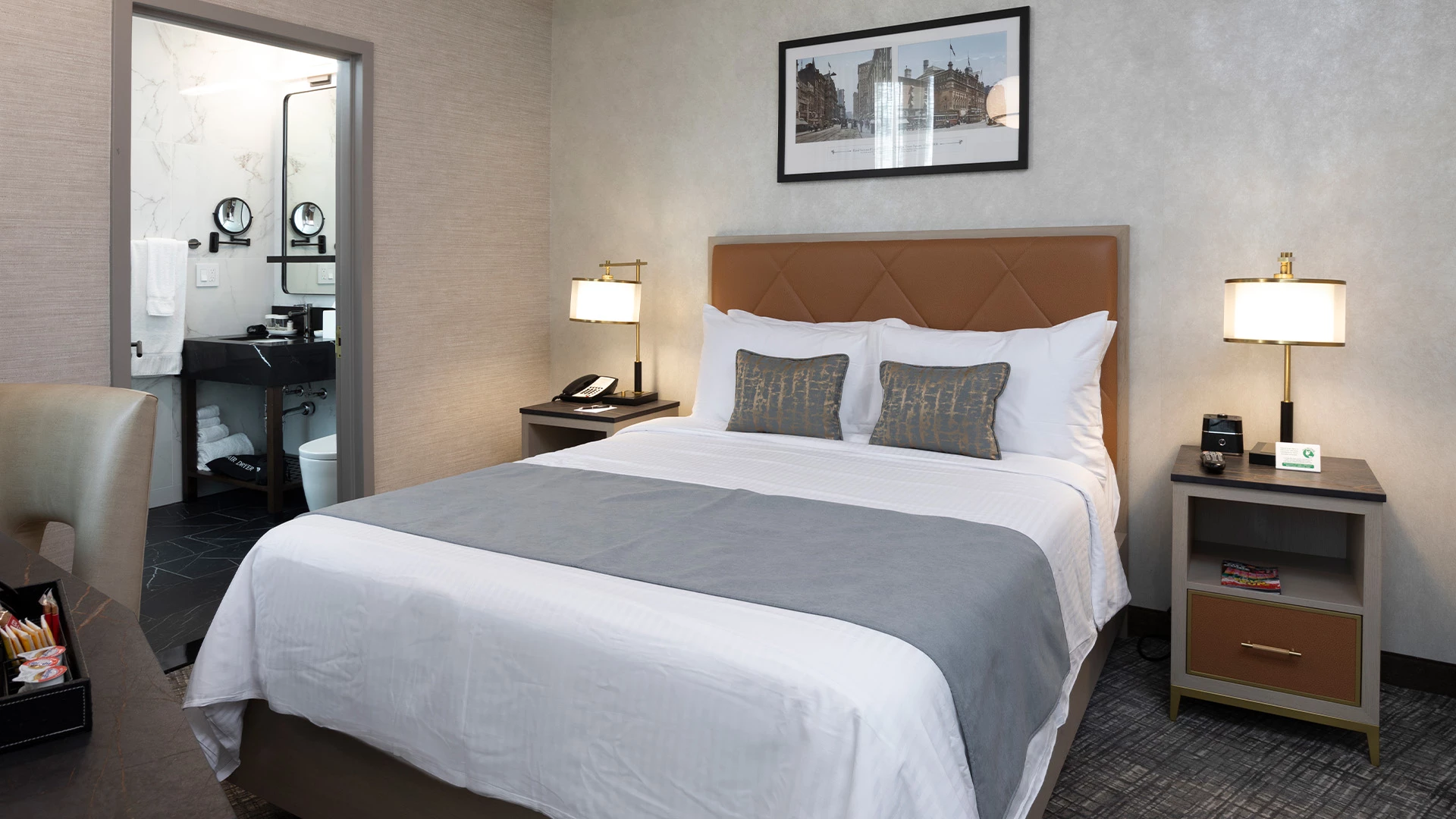 A hotel room with a bed, nightstands, and a bathroom in the background.