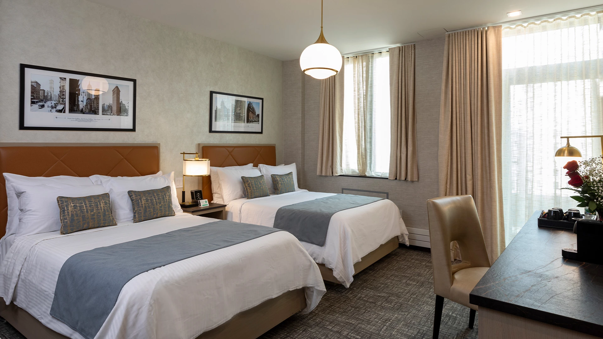 A hotel room with two beds, a desk, and a window