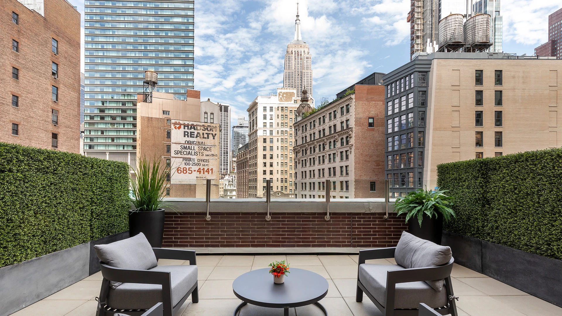 A rooftop patio with outdoor seating and a city view