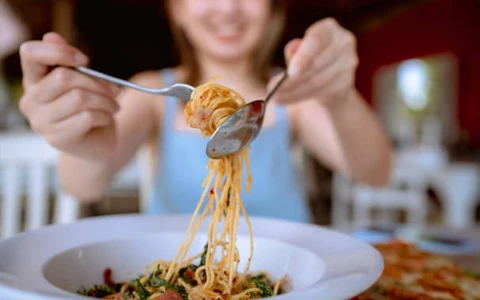 A woman eating spaghetti with a fork and knife