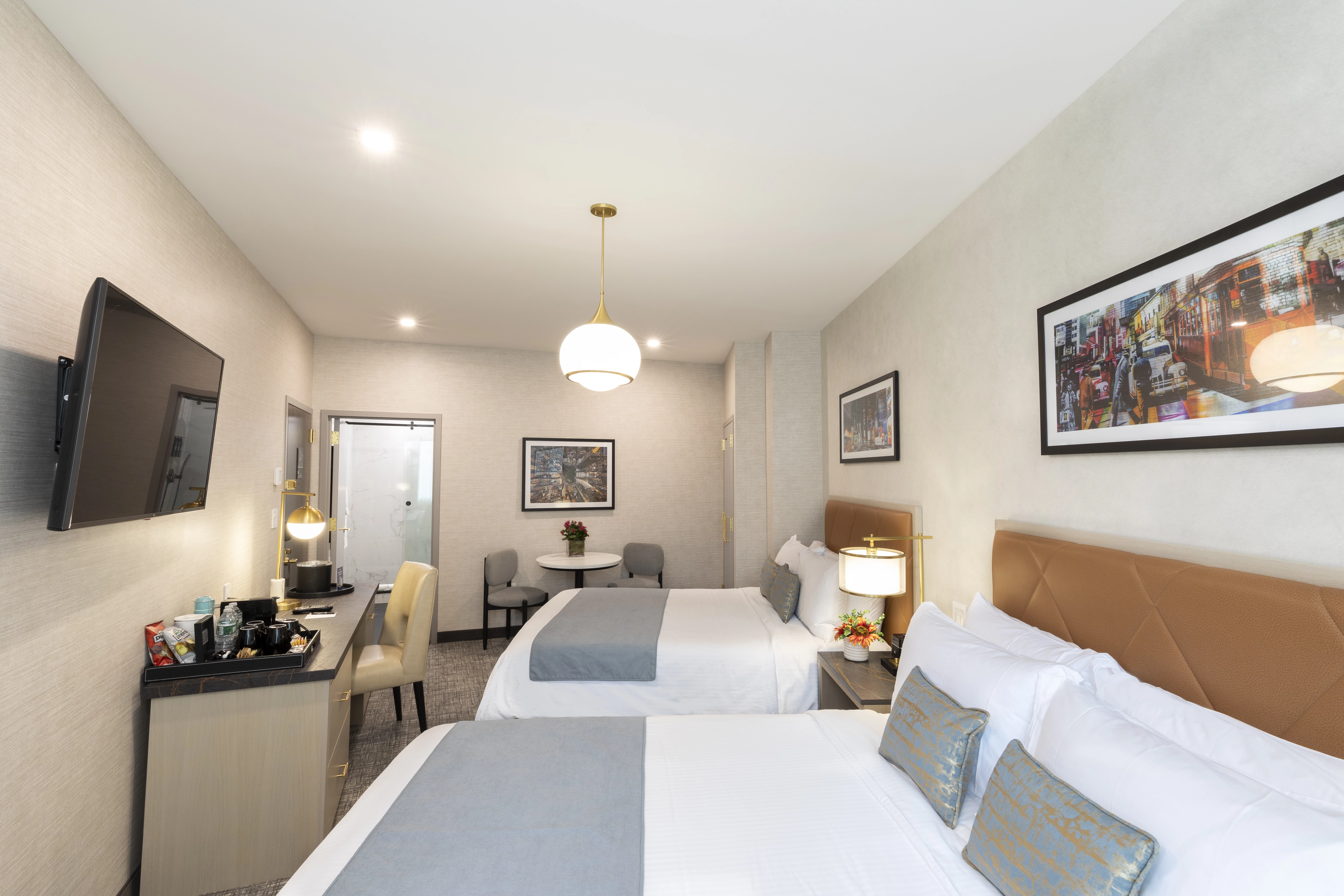 A hotel room with two beds, a TV, desk, table, and chairs