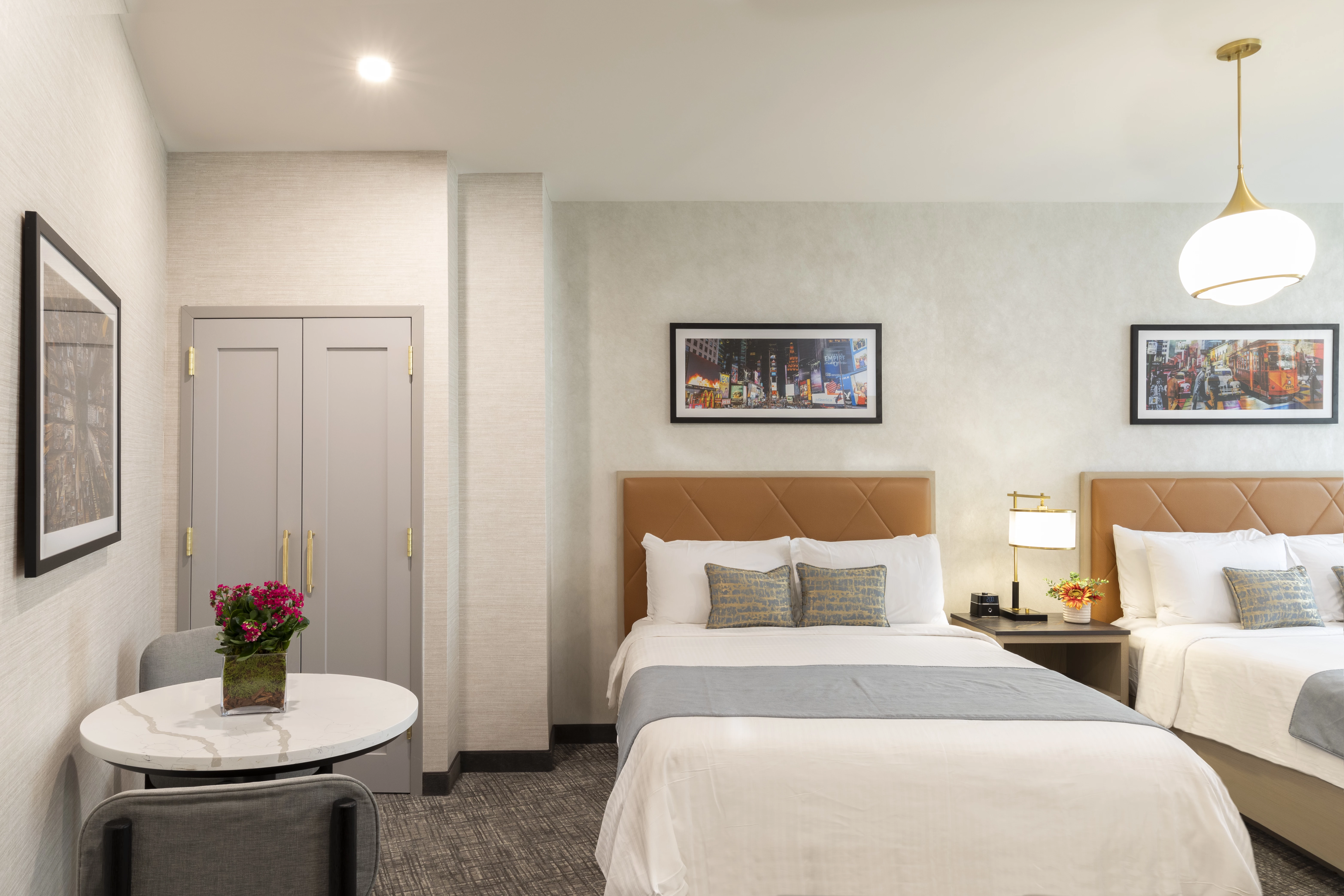 A hotel room with two beds, a table, and chairs.