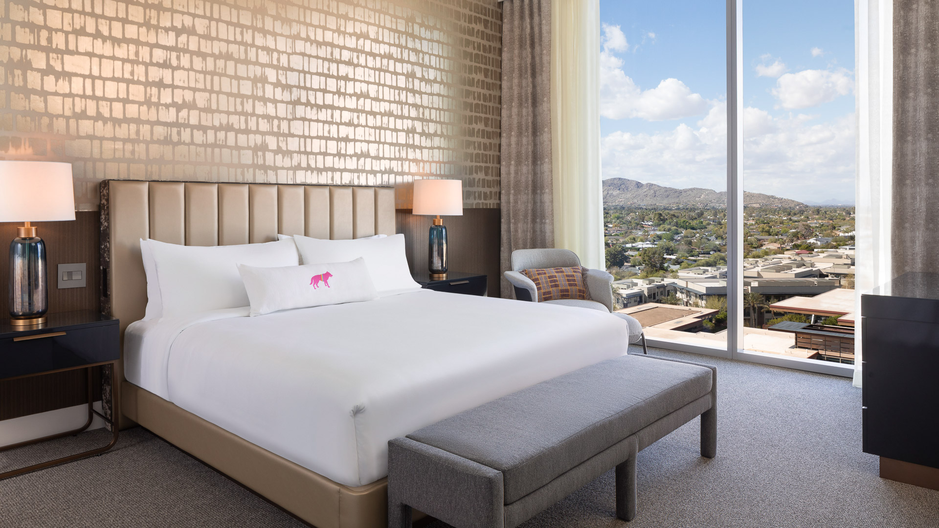 a bed with a bench and a lamp in a room with a view of a city