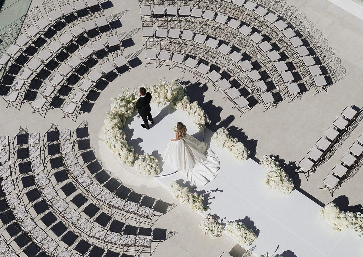 a bride and groom standing on a stage with chairs