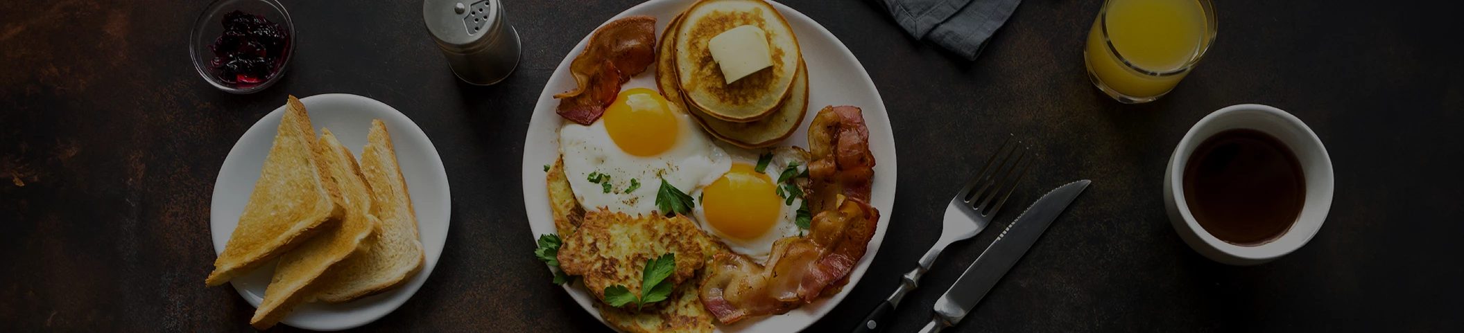 a plate of food with eggs bacon pancakes and butter
