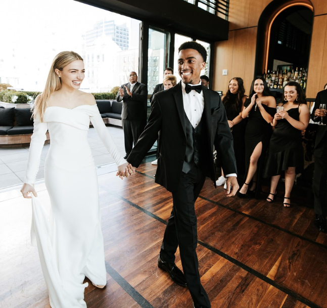 a man and woman in a tuxedo holding hands and dancing